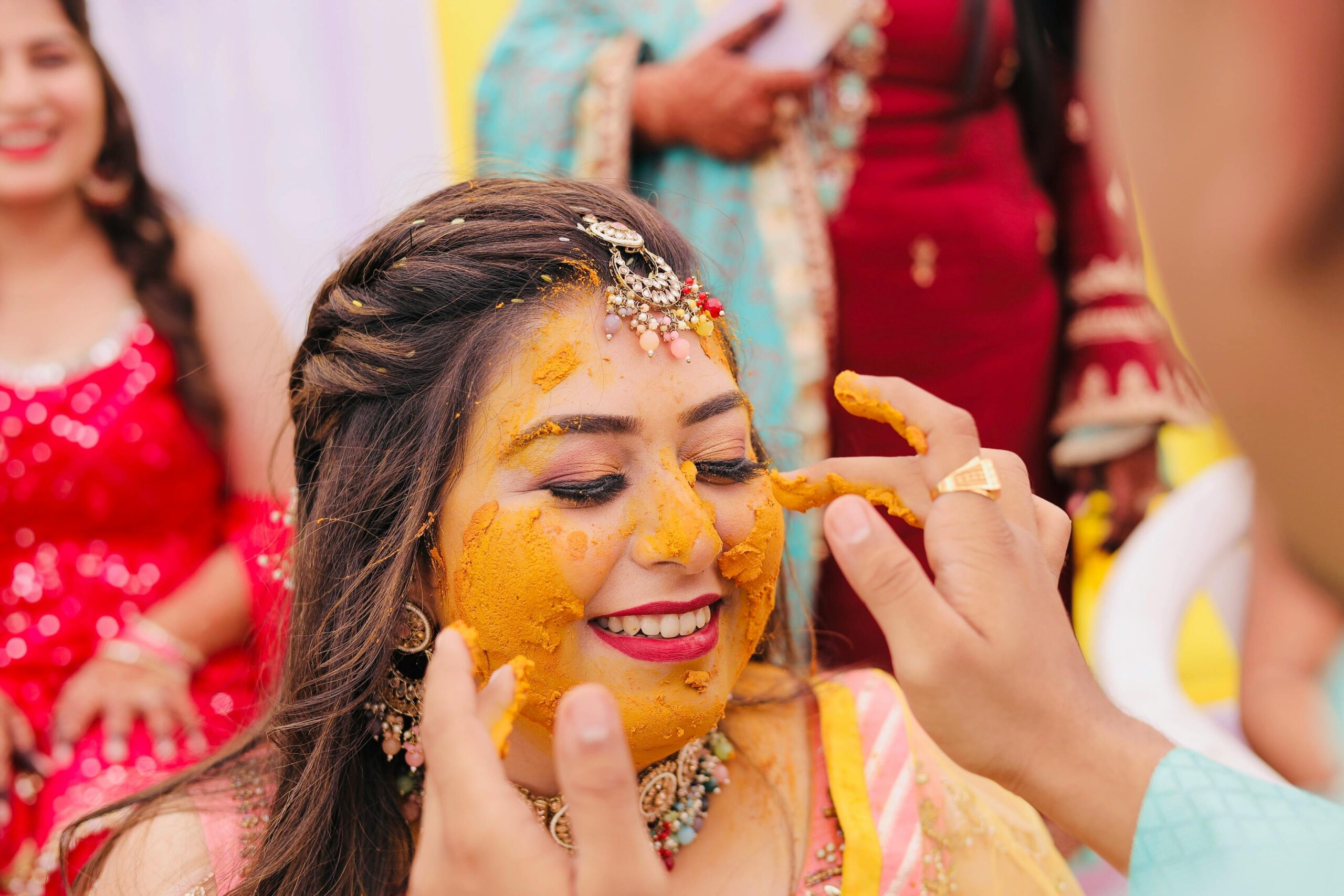 A joyful moment during a traditional Indian Haldi ceremony with vibrant colors and smiling faces.